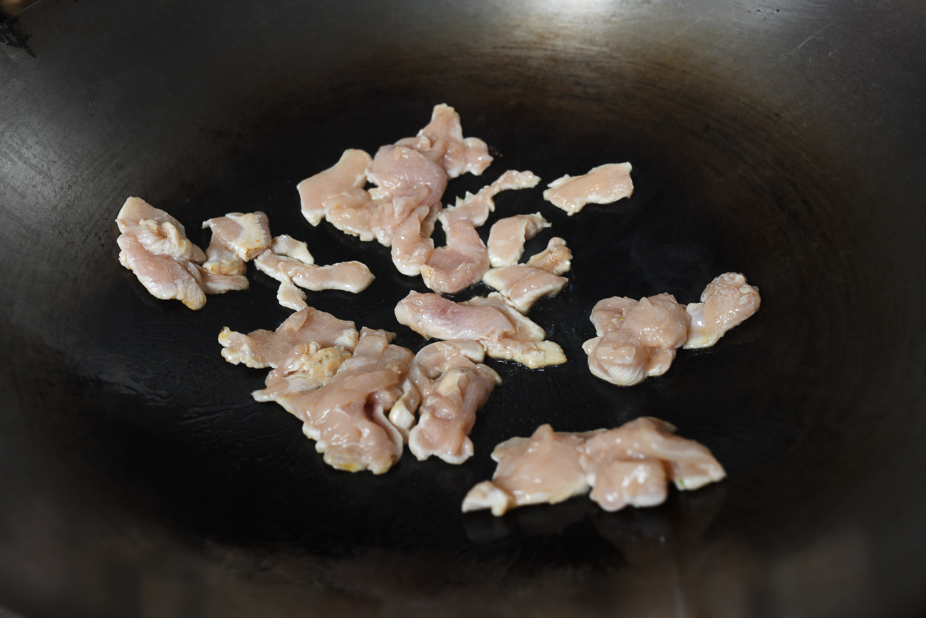 Searing sliced chicken in wok