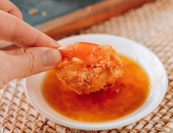 dipping coconut shrimp into sauce