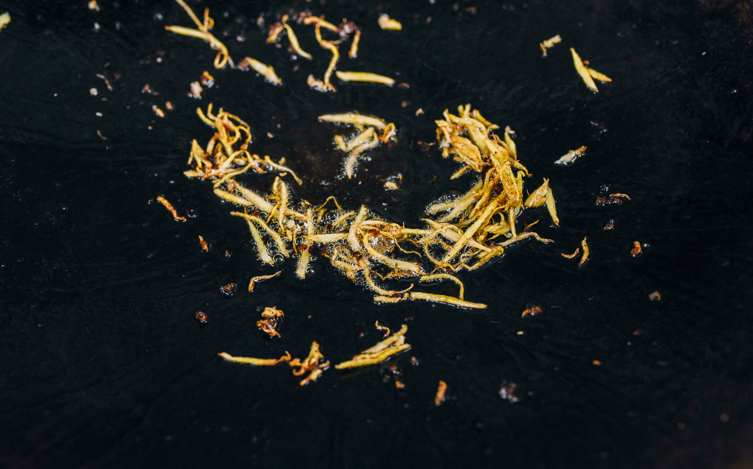 caramelized pieces of julienned ginger in a wok