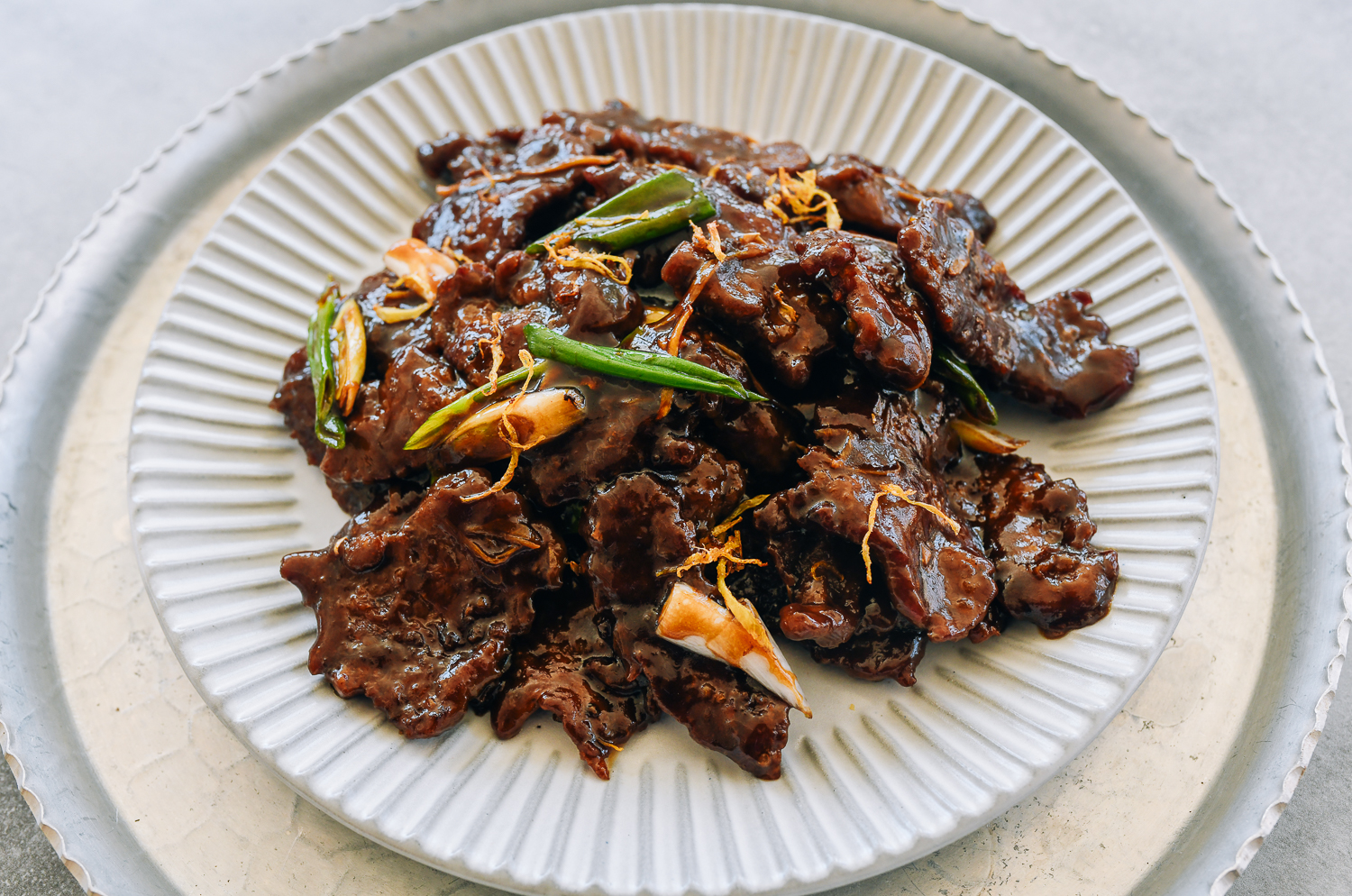 plate of ginger beef garnished with caramelized frizzled ginger