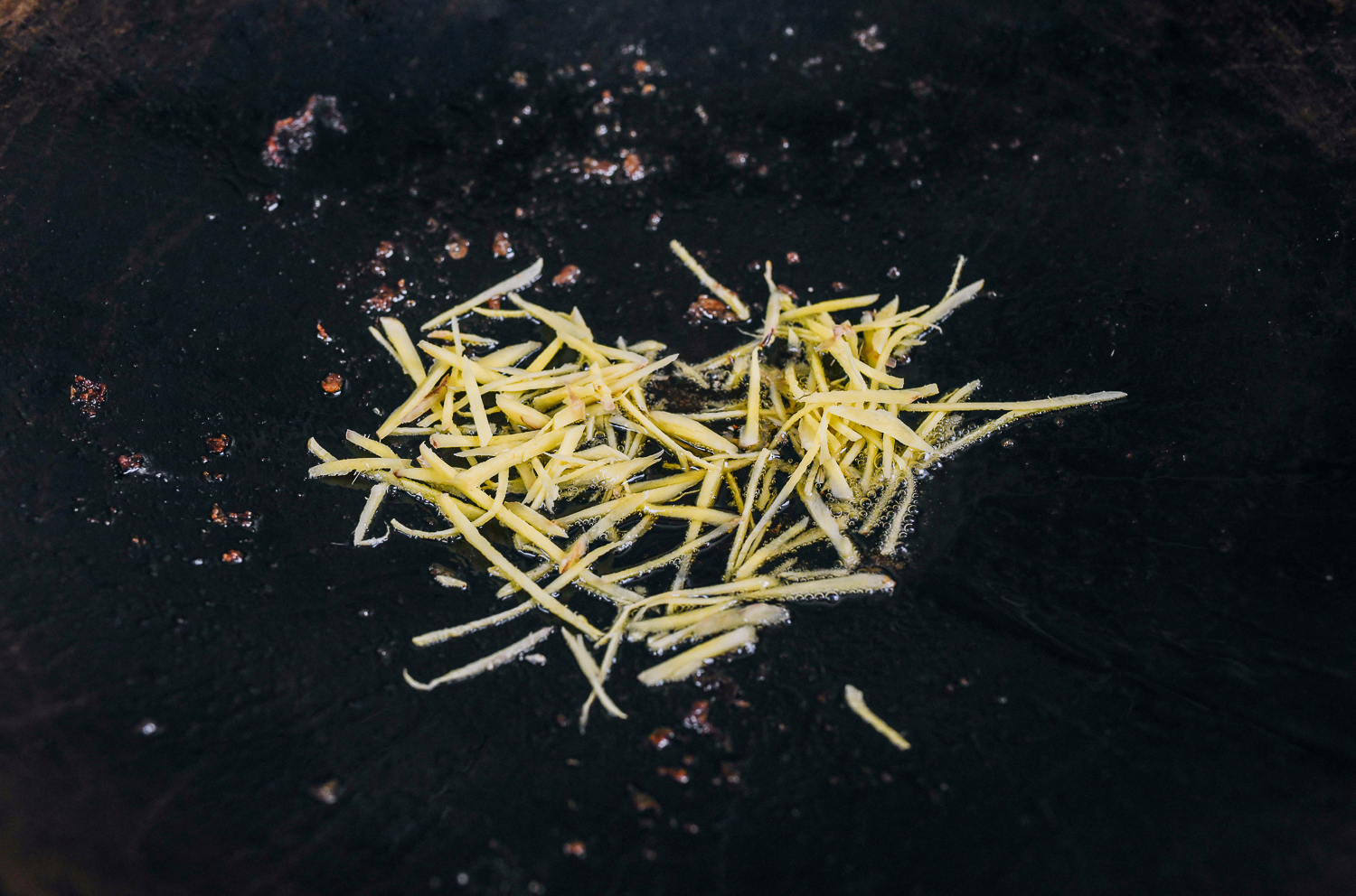 julienned ginger in oil in wok